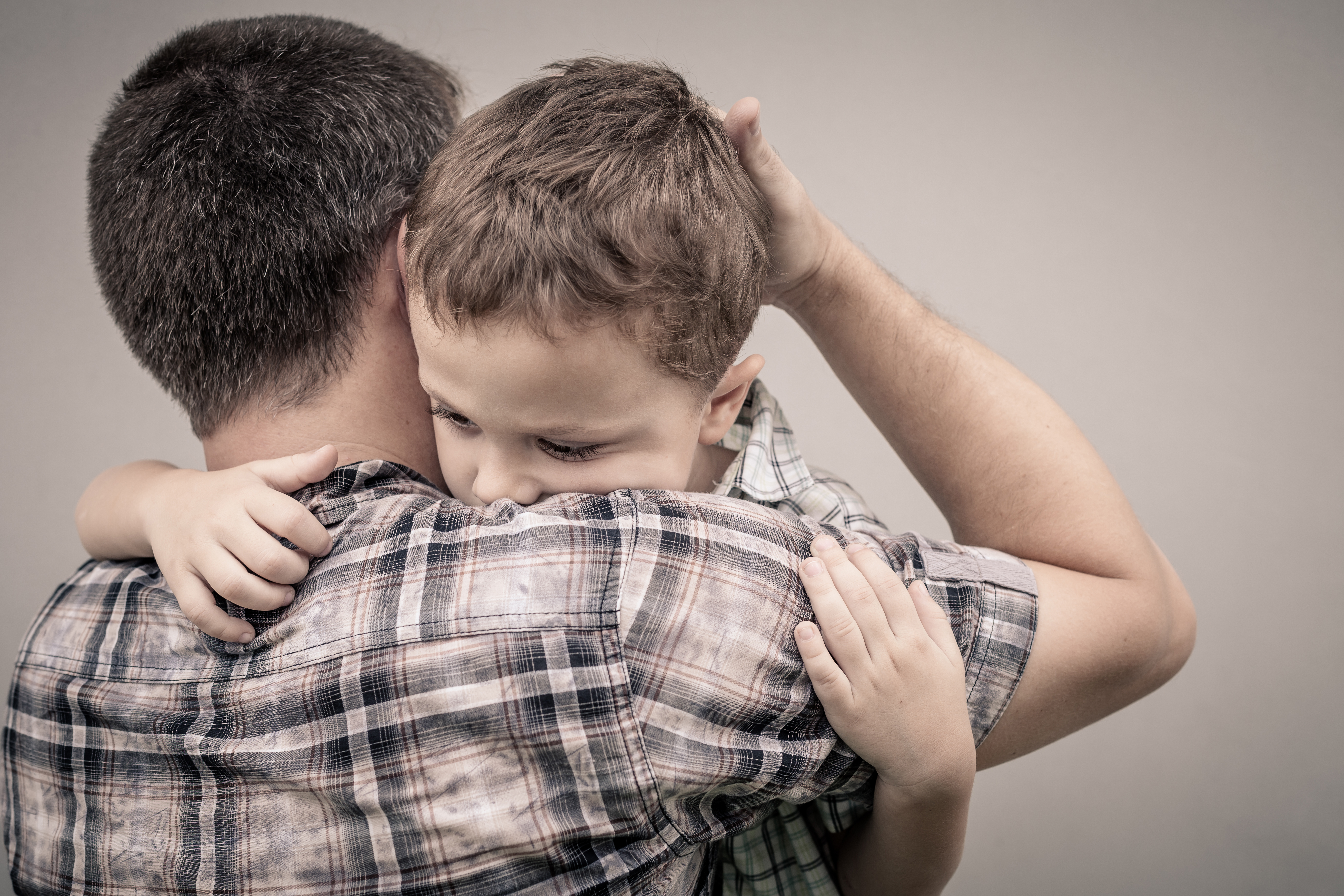 A father hugging his sad-looking son | Source: Shutterstock