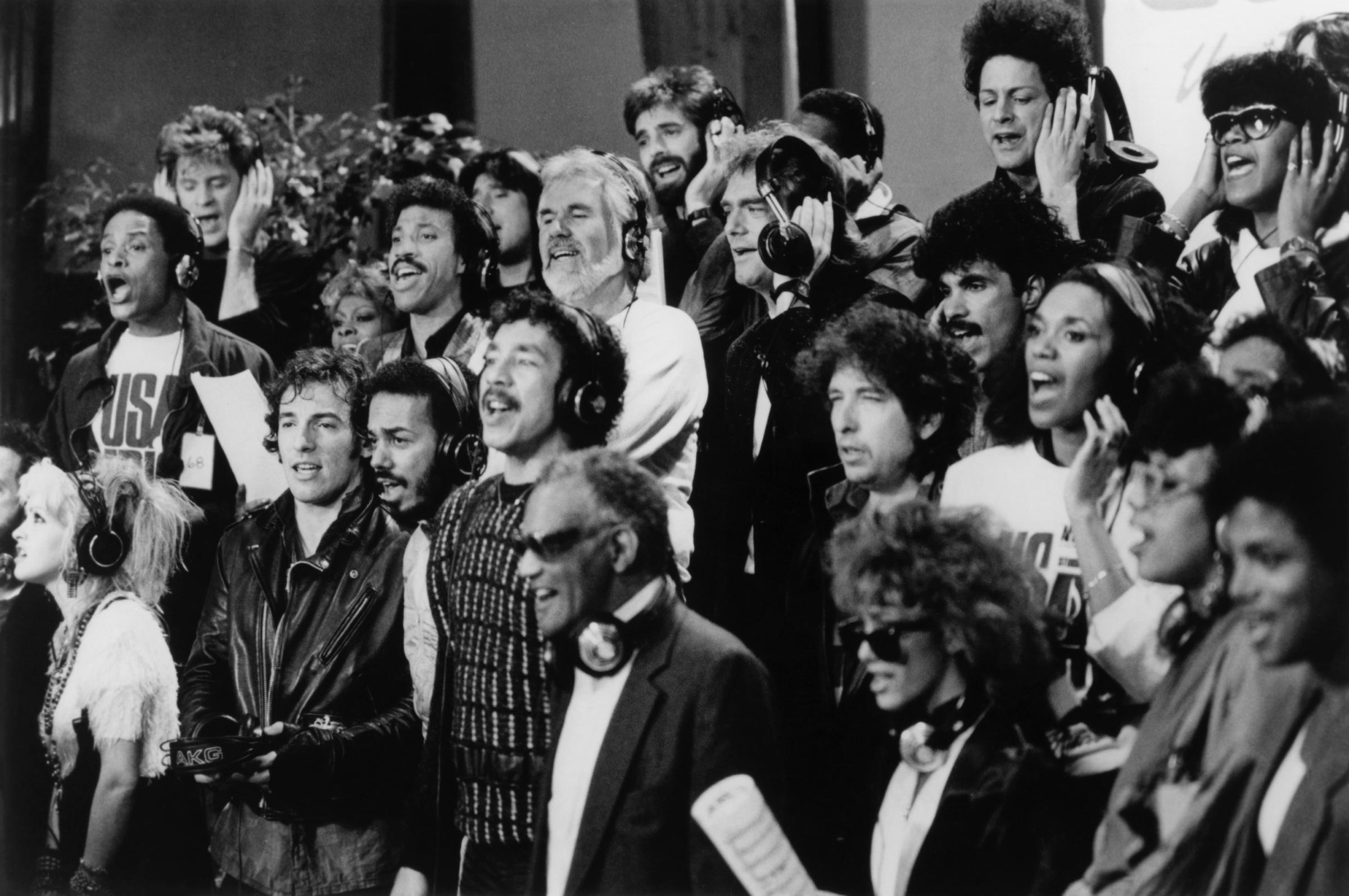 Al Jarreau, Lionel Richie, Kenny Rogers, Cindy Lauper, Bruce Springsteen, James Ingram, Bob Dylan, Dionne Warwick, and Ray Charles, among others, singing "We Are the World" on January 28, 1985 | Source: Getty Images